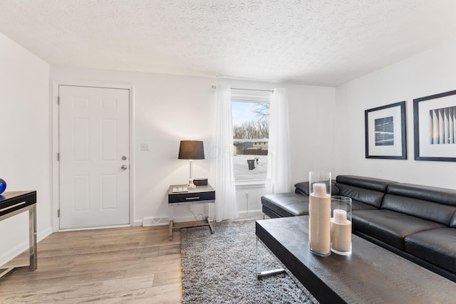 living room featuring light wood-type flooring and a textured ceiling