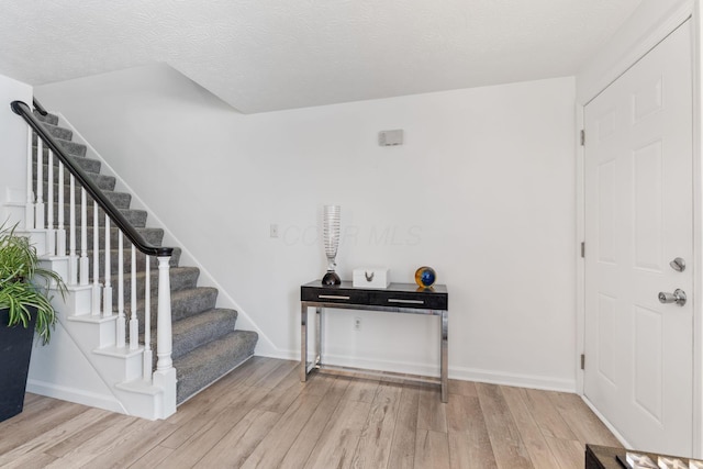 foyer entrance with a textured ceiling and light hardwood / wood-style floors