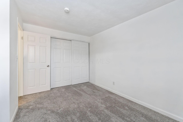 unfurnished bedroom featuring light colored carpet and a closet