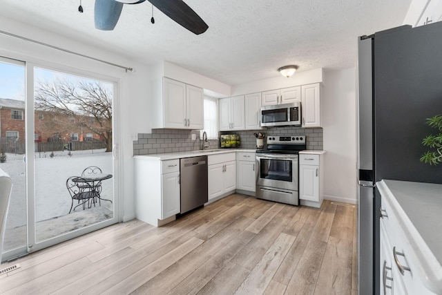 kitchen featuring decorative backsplash, appliances with stainless steel finishes, sink, and white cabinetry