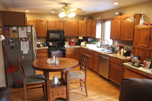 kitchen with light wood-type flooring, ceiling fan, black appliances, and sink