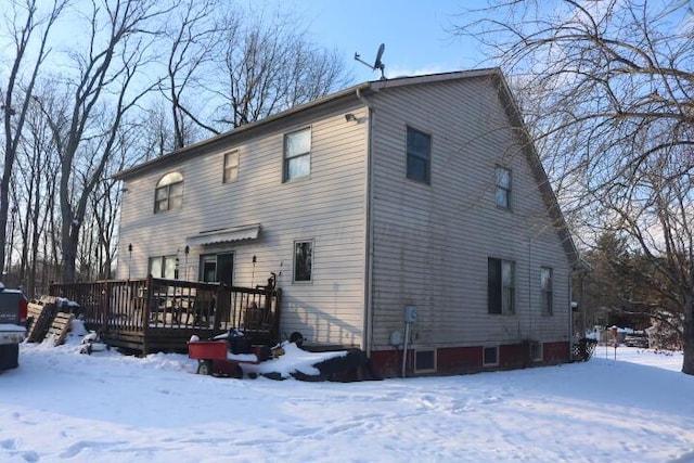 snow covered back of property with a wooden deck