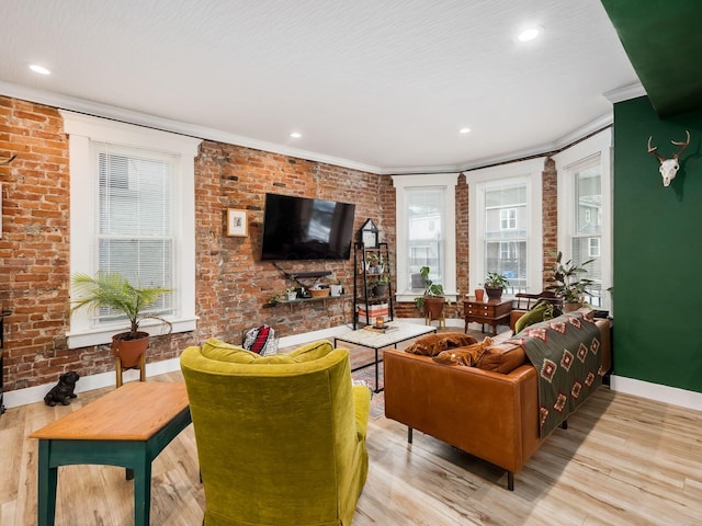 living room featuring crown molding, light hardwood / wood-style flooring, and brick wall