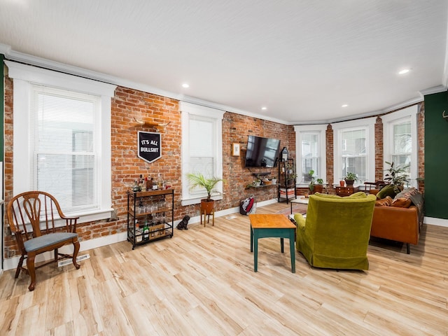 living room featuring light hardwood / wood-style flooring, brick wall, and ornamental molding