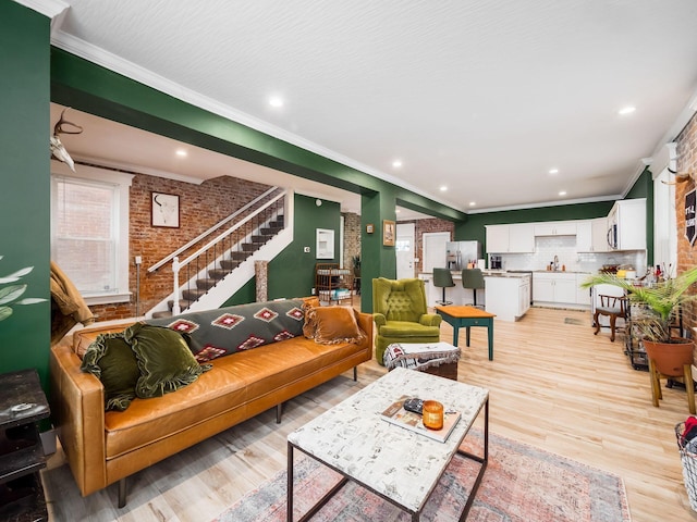 living room with brick wall, crown molding, and light hardwood / wood-style floors