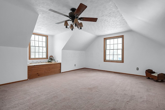 bonus room featuring a textured ceiling, ceiling fan, light colored carpet, and vaulted ceiling