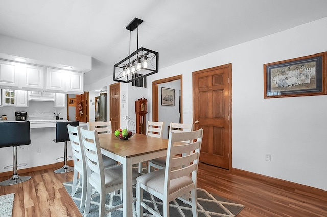 dining area with light wood-type flooring and a notable chandelier