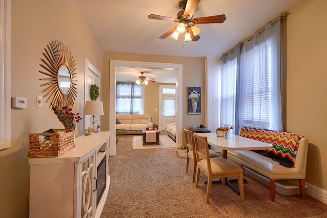 carpeted dining area with ceiling fan