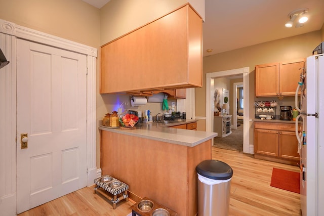 kitchen featuring white refrigerator, sink, kitchen peninsula, and light hardwood / wood-style floors