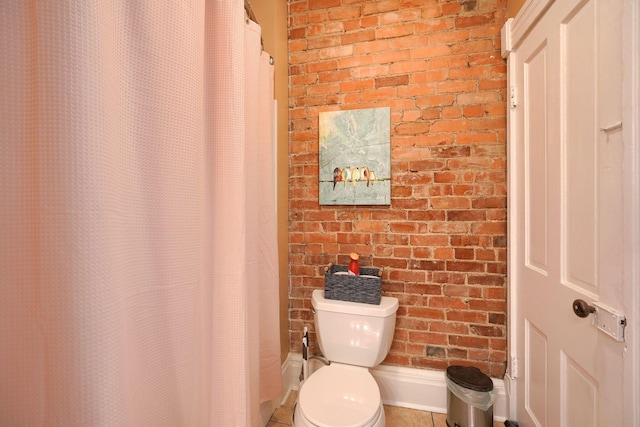 bathroom with brick wall and toilet