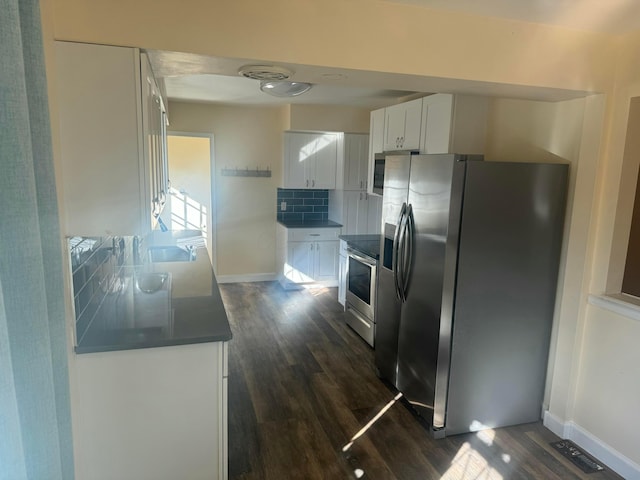 kitchen with decorative backsplash, white cabinetry, dark wood-type flooring, and appliances with stainless steel finishes