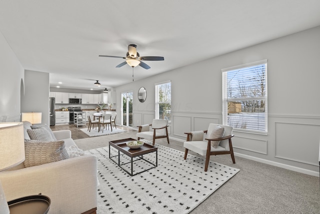 living room featuring ceiling fan, light colored carpet, and plenty of natural light