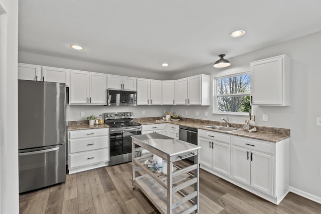 kitchen featuring sink, white cabinets, light hardwood / wood-style flooring, and appliances with stainless steel finishes