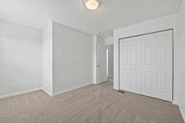 unfurnished bedroom featuring a closet and light colored carpet