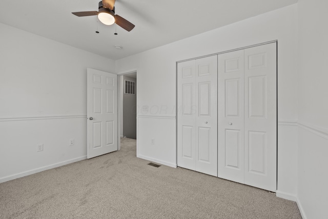 unfurnished bedroom with light colored carpet, a closet, and ceiling fan