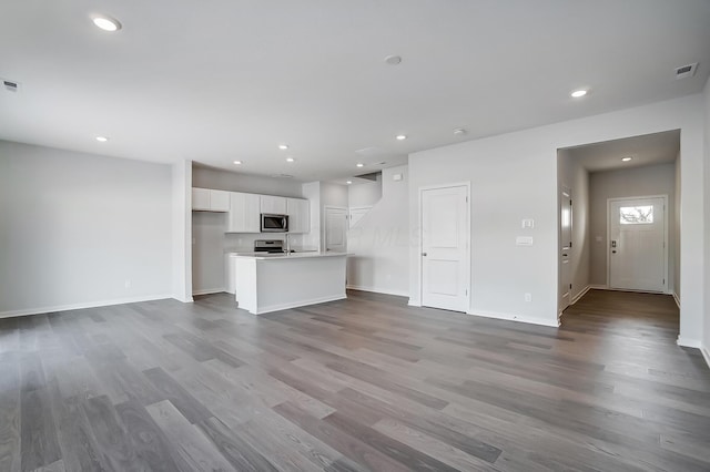 unfurnished living room with visible vents, recessed lighting, baseboards, and wood finished floors