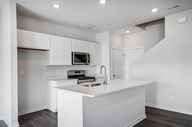 kitchen featuring visible vents, a kitchen island with sink, a sink, stainless steel appliances, and white cabinets