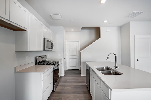 kitchen with visible vents, dark wood finished floors, an island with sink, stainless steel appliances, and a sink