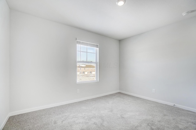 carpeted empty room featuring baseboards