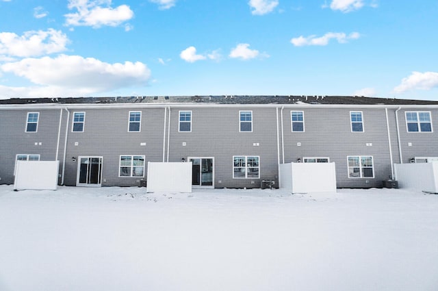 snow covered rear of property with fence