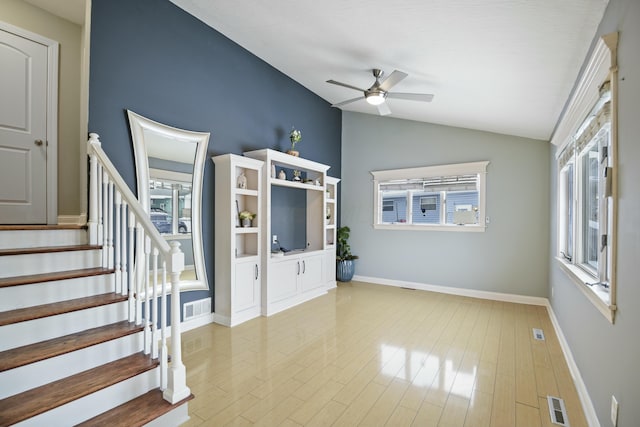 unfurnished living room with ceiling fan, vaulted ceiling, and light wood-type flooring