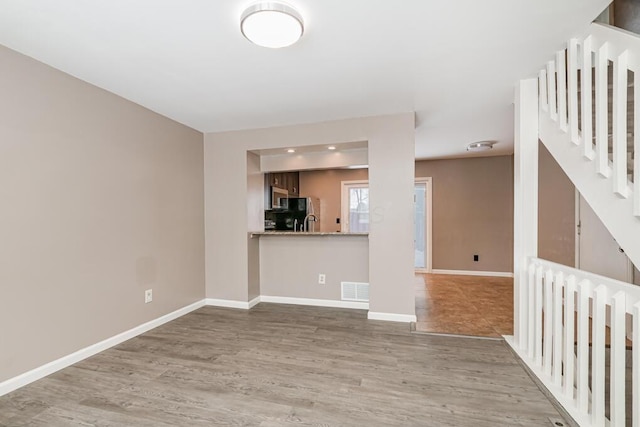 unfurnished living room featuring light wood-type flooring and sink