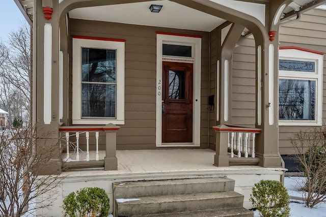 snow covered property entrance featuring a porch