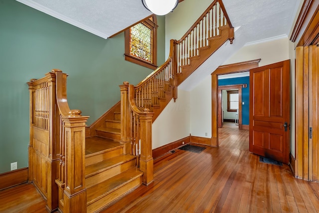 staircase featuring crown molding, a textured ceiling, and hardwood / wood-style flooring