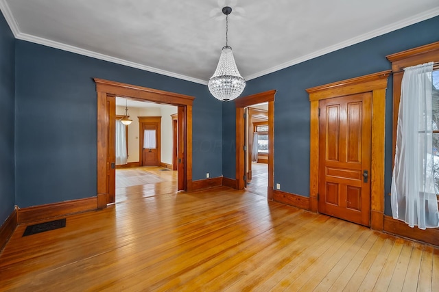 empty room featuring ornamental molding, light hardwood / wood-style flooring, and a chandelier