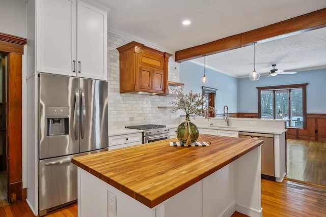 kitchen featuring a center island, white cabinets, sink, appliances with stainless steel finishes, and decorative light fixtures