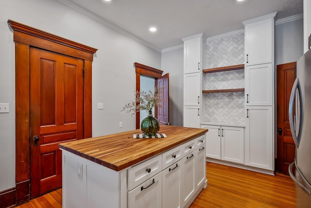 kitchen with backsplash, stainless steel refrigerator, white cabinets, and ornamental molding