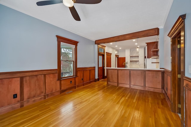 kitchen featuring ceiling fan, hanging light fixtures, tasteful backsplash, kitchen peninsula, and light wood-type flooring