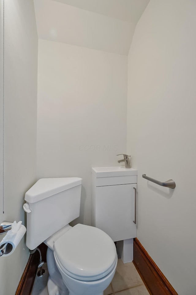 bathroom with tile patterned floors, toilet, lofted ceiling, and sink