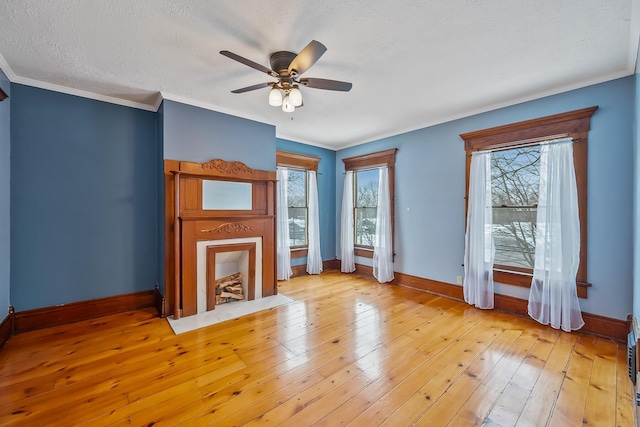 unfurnished living room featuring a textured ceiling, light hardwood / wood-style floors, ceiling fan, and ornamental molding