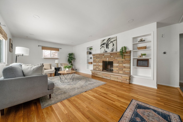 living room featuring hardwood / wood-style flooring, built in features, and a fireplace