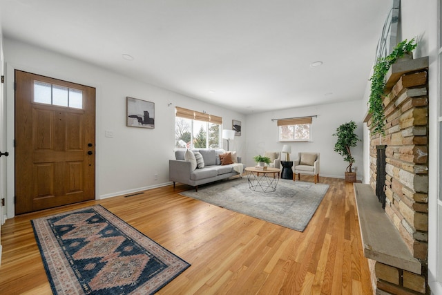 living room featuring light hardwood / wood-style floors and a stone fireplace