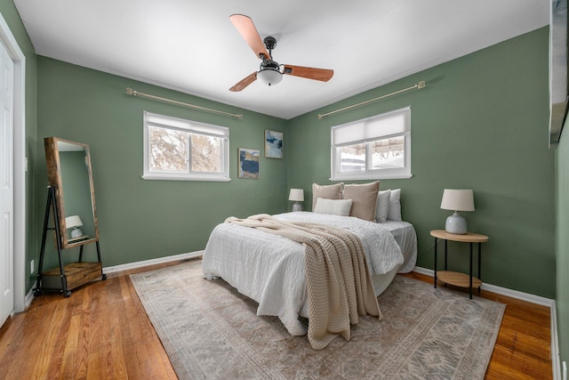 bedroom featuring ceiling fan, hardwood / wood-style floors, and multiple windows