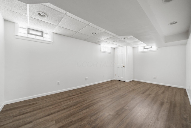 basement with a paneled ceiling and dark hardwood / wood-style flooring