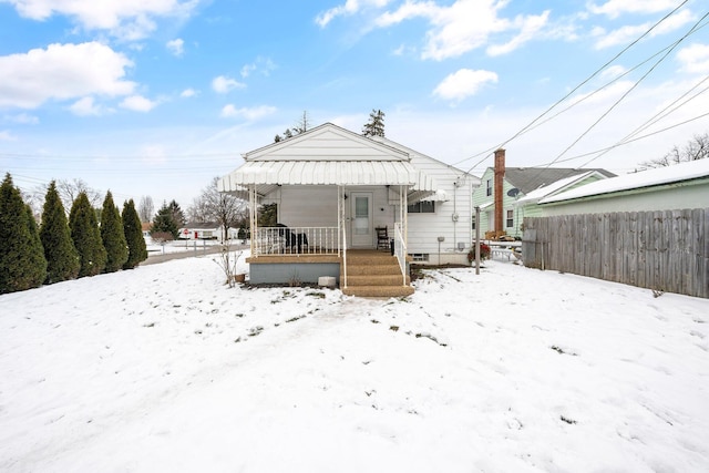 snow covered rear of property featuring covered porch