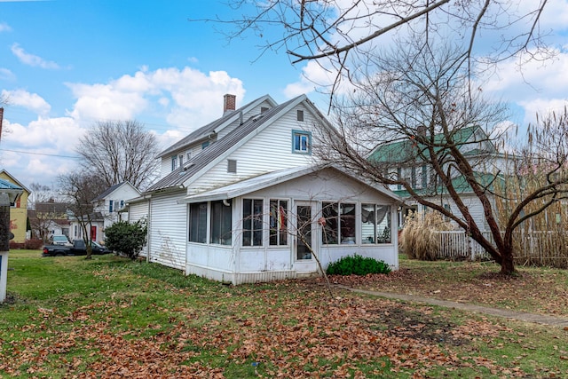 rear view of house with a sunroom and a yard