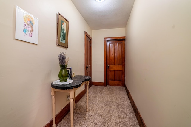 corridor featuring light carpet and a textured ceiling