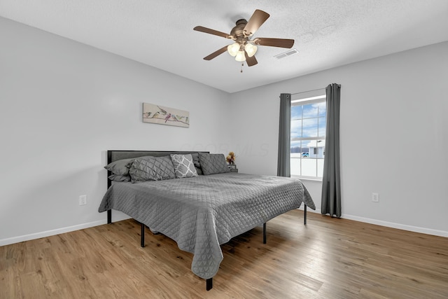 bedroom featuring a textured ceiling, light wood-type flooring, and ceiling fan