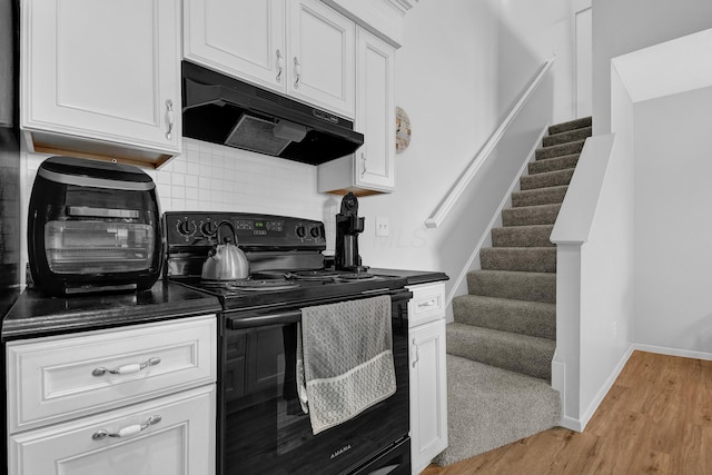 kitchen featuring tasteful backsplash, white cabinetry, black electric range, and light wood-type flooring