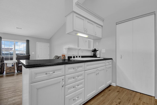 kitchen with kitchen peninsula, decorative backsplash, white cabinets, and sink