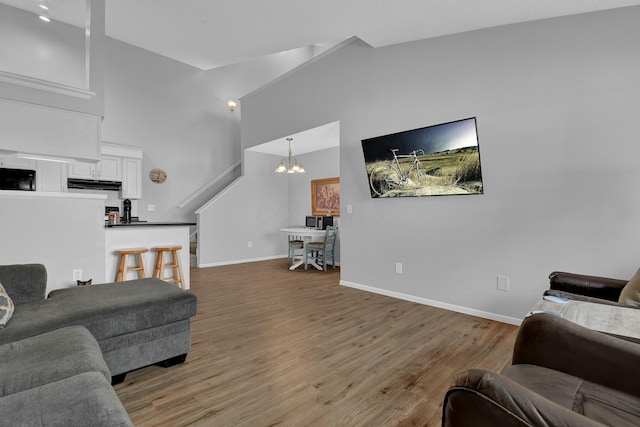 living room featuring hardwood / wood-style floors, lofted ceiling, and an inviting chandelier