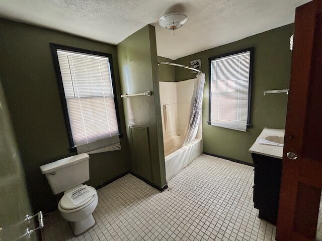 full bathroom featuring vanity, a textured ceiling, toilet, and shower / tub combo with curtain