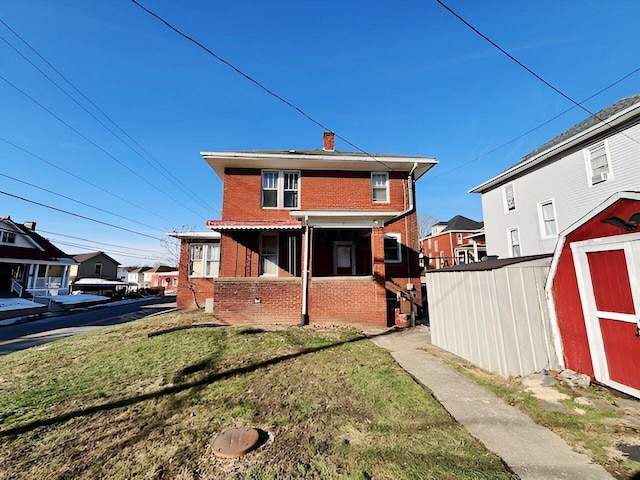 back of house with an outbuilding, a shed, a yard, brick siding, and a chimney