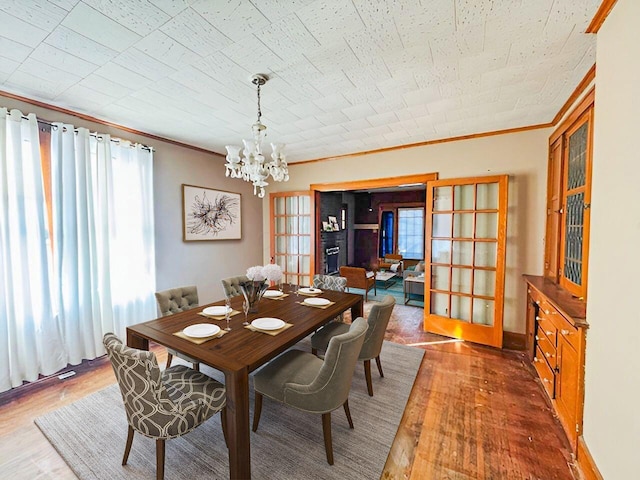 dining space featuring a chandelier, french doors, crown molding, and wood finished floors