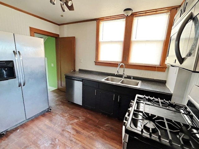 kitchen with a sink, wood finished floors, dark cabinetry, stainless steel appliances, and crown molding