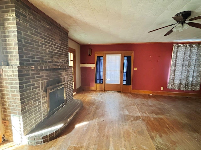 unfurnished living room with baseboards, a ceiling fan, wood finished floors, and a fireplace